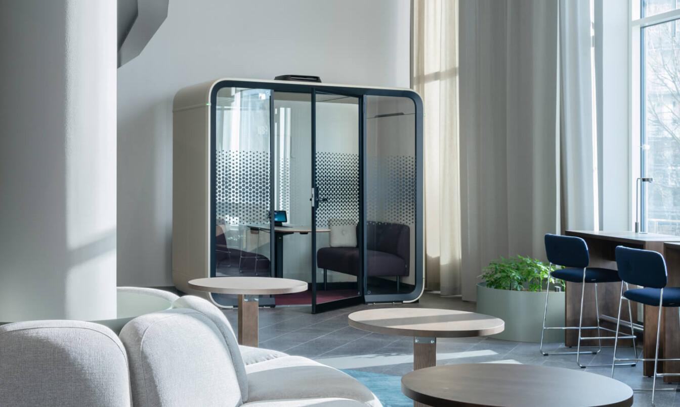 A sand colored office pod in an office lobby.