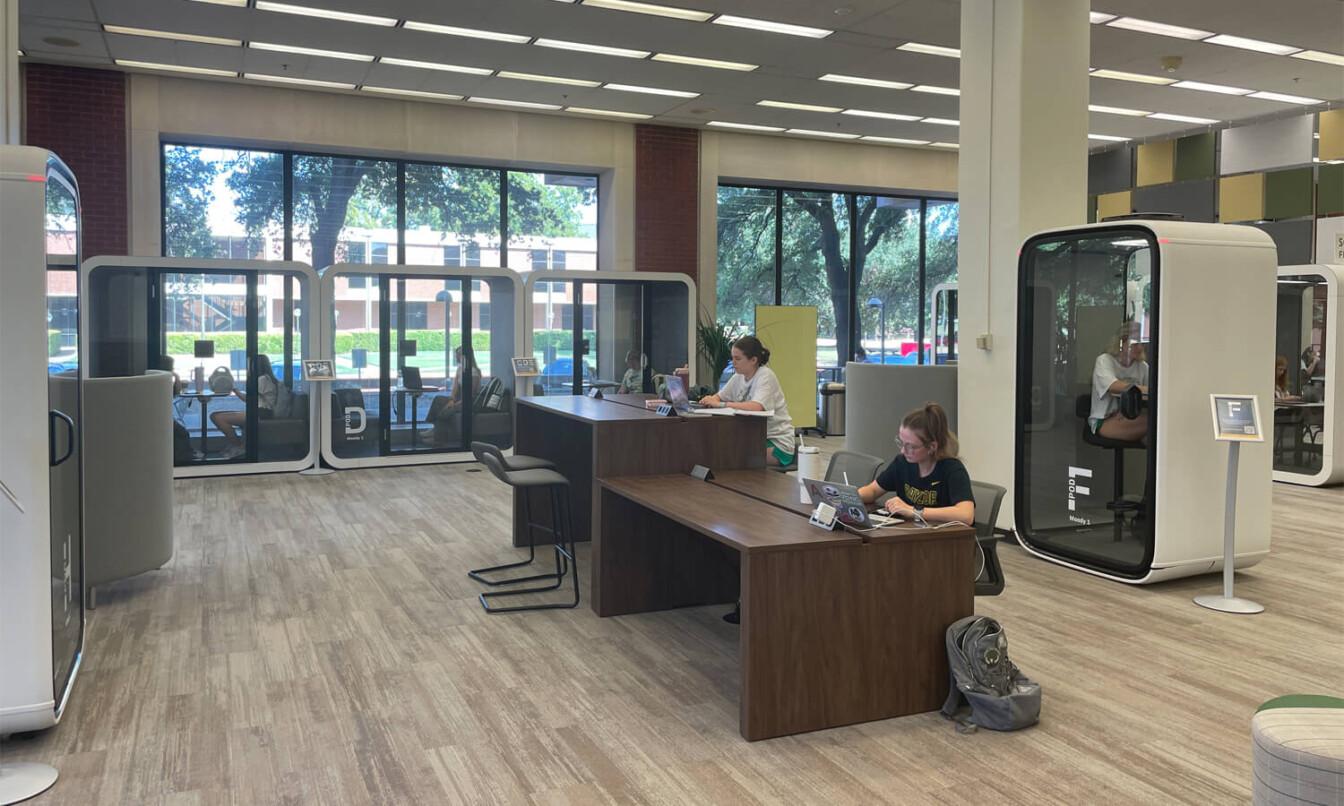 Univesity library with students and study pods.