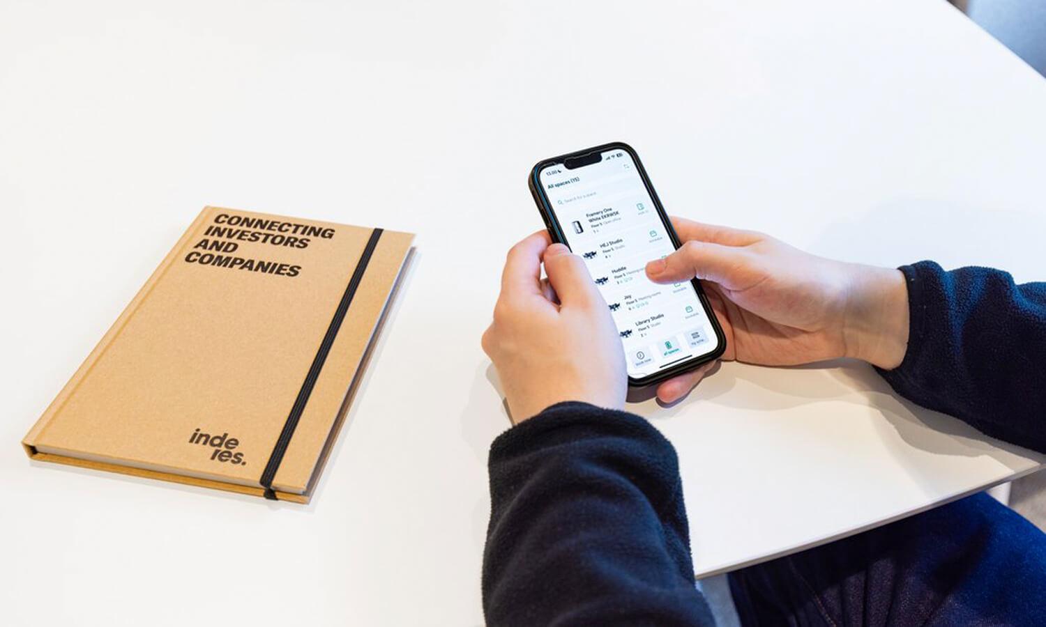 Hands holding a mobile phone on top of a table.