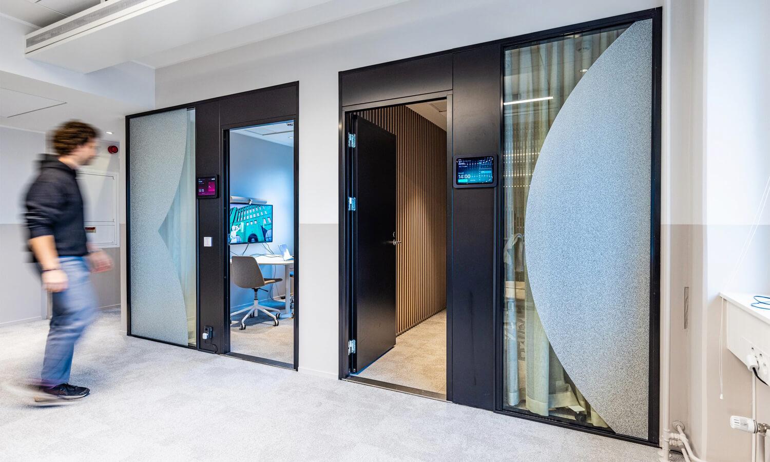 An office hallway with two meeting rooms with doors open.