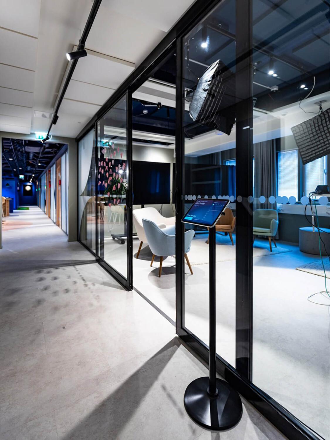 An office meeting room with glass walls in a long corridor.