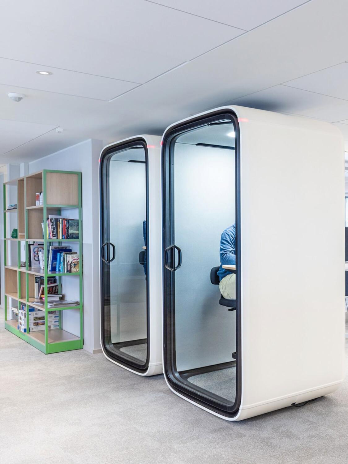 Two white Framery One pods side by side in a hallway.