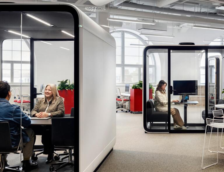 White Framery meeting pods in an office with people inside.
