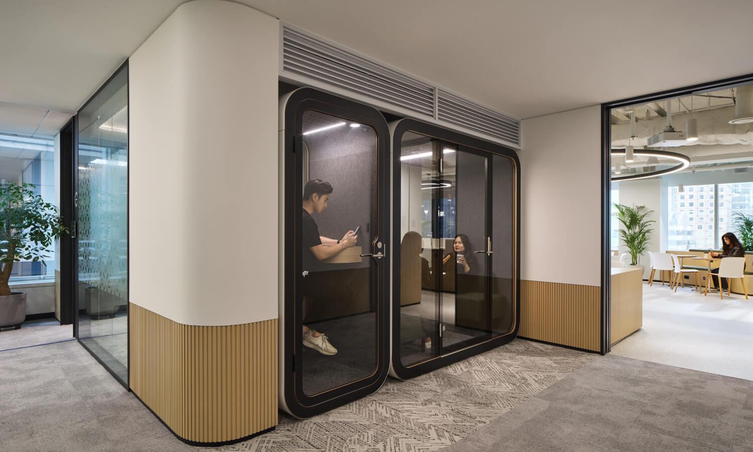 People working in office pods that are integrated into the wall structure.