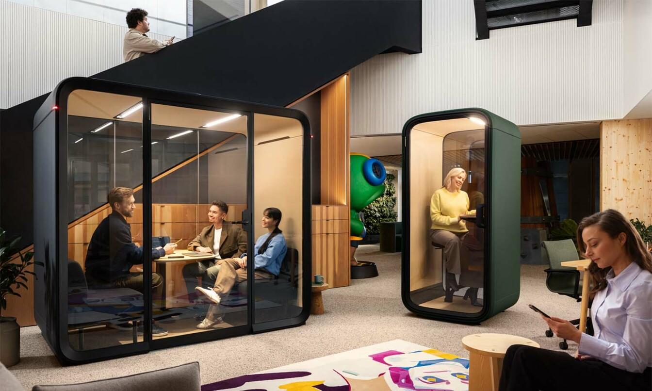 People working in and around office pods in a modern open plan office. 