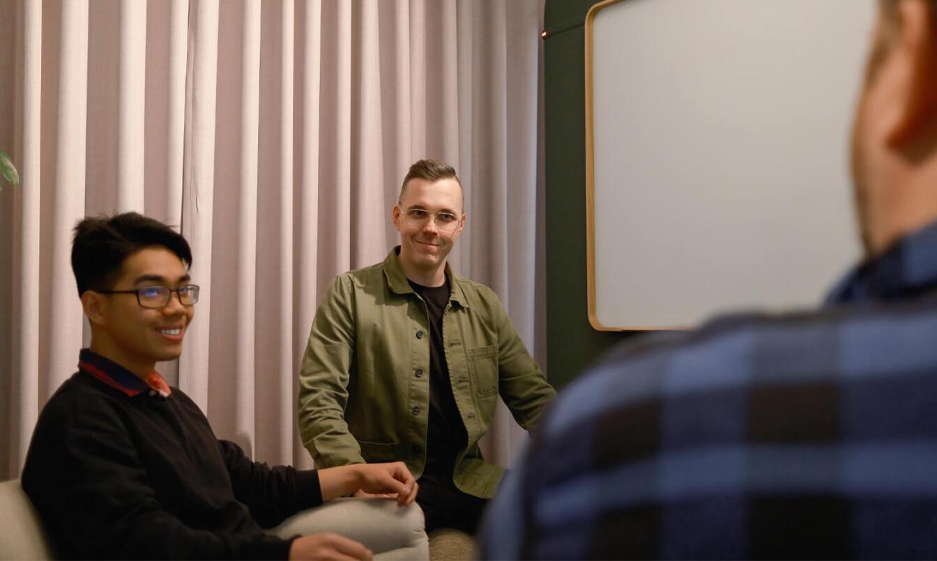 Two men facing the camera talking to a third one with his back to the camera.